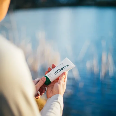 Xylocap Aktiv värmande liniment i tub liggande i gräs